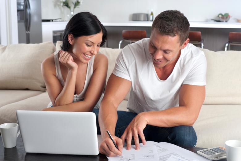 Young Couple reviewing their financial plan while sitting on a couch in their living room. 
