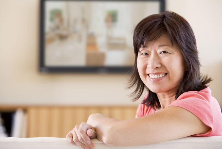 Older women sitting on her couch smiling