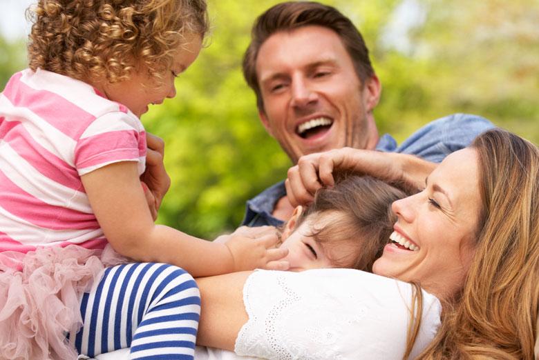 Family with young children lying on the grass playing and smiling